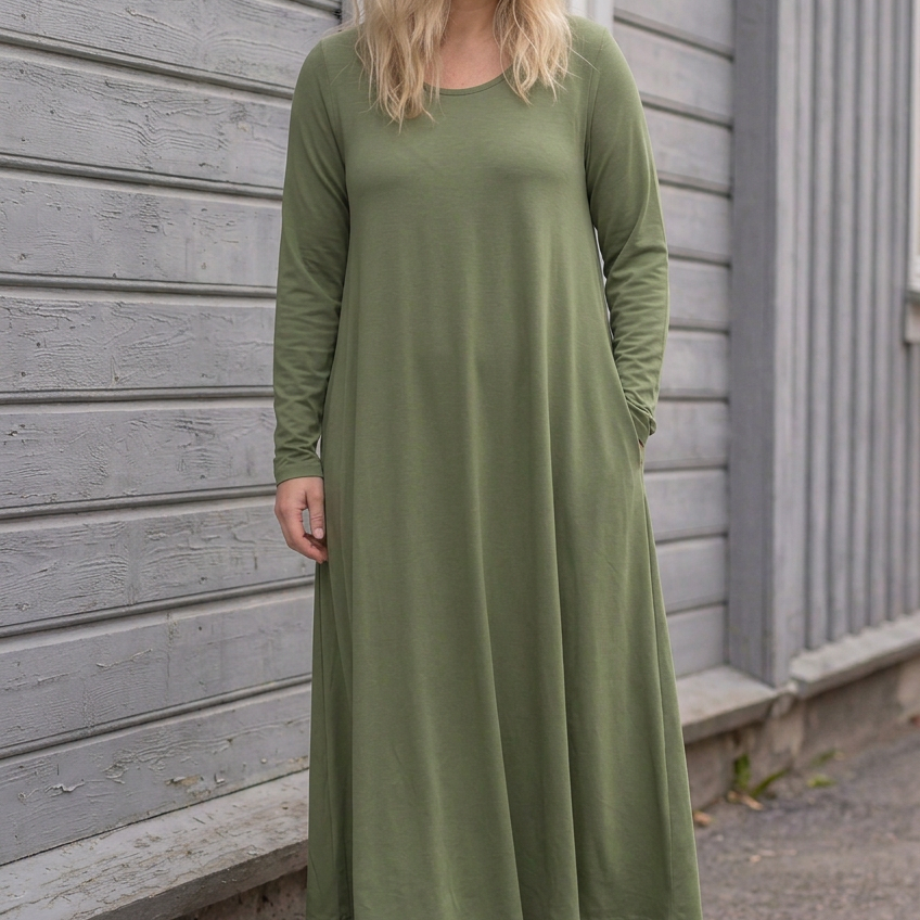 Blond modell i grön Ballerina Long Sleeve, lätt lutande mot träfasaden