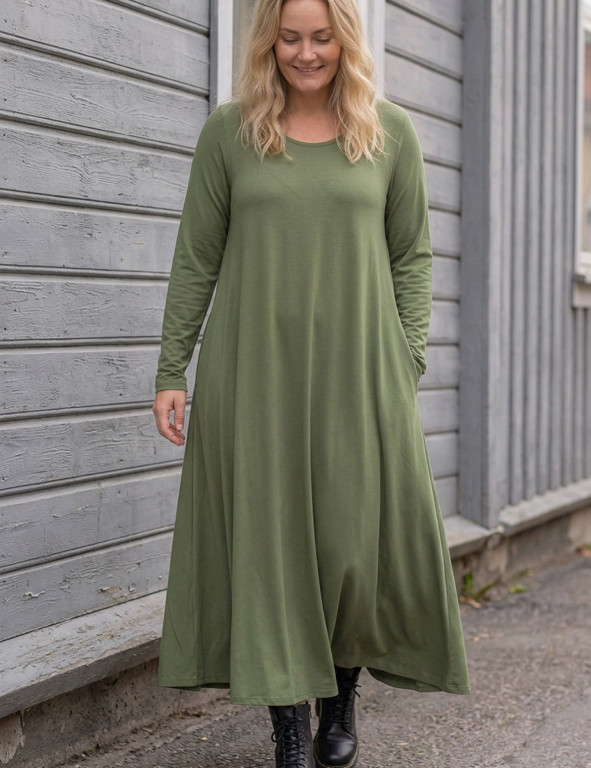Blond modell i grön Ballerina Long Sleeve, gående längs träfasaden