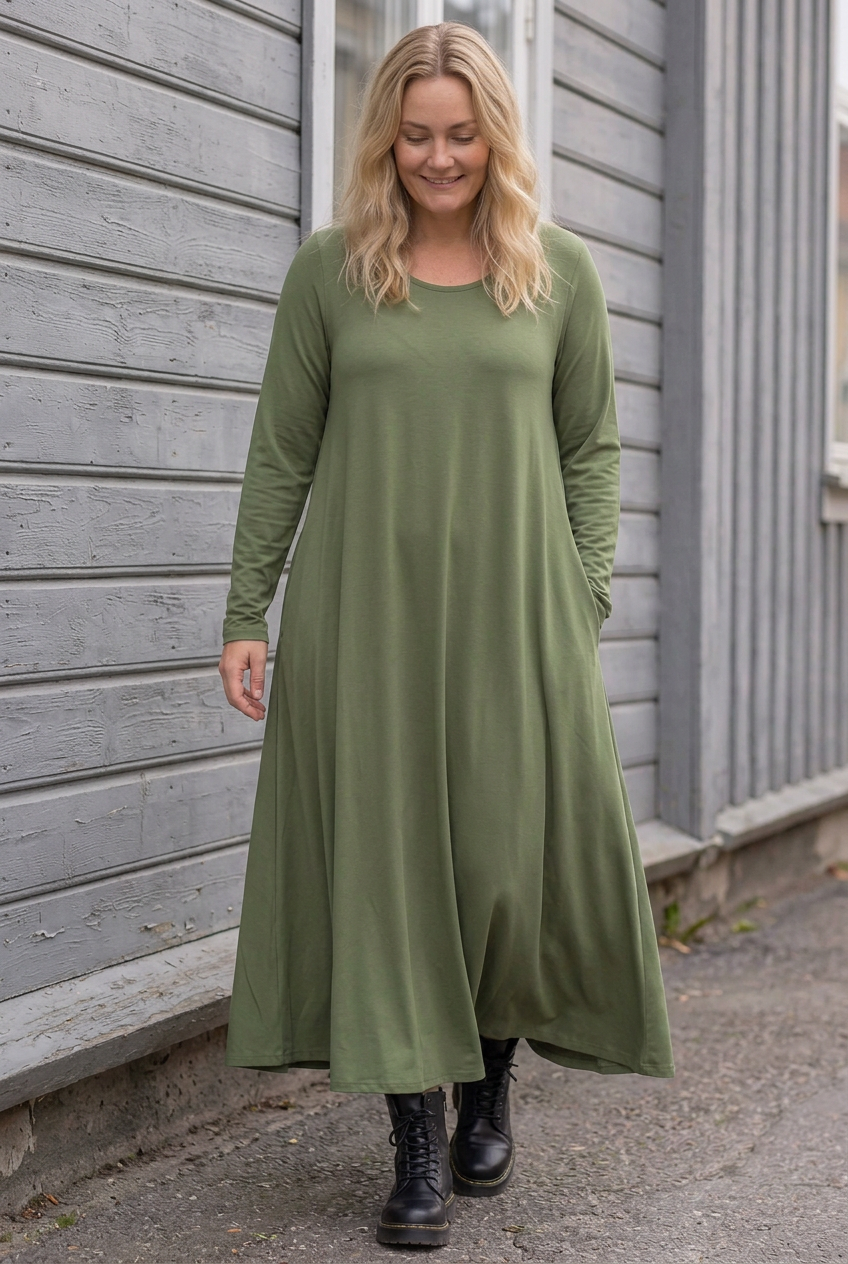 Blond modell i grön Ballerina Long Sleeve, gående längs träfasaden