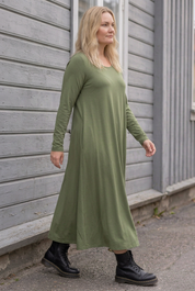 Blond modell i grön klänning, gående från sidan